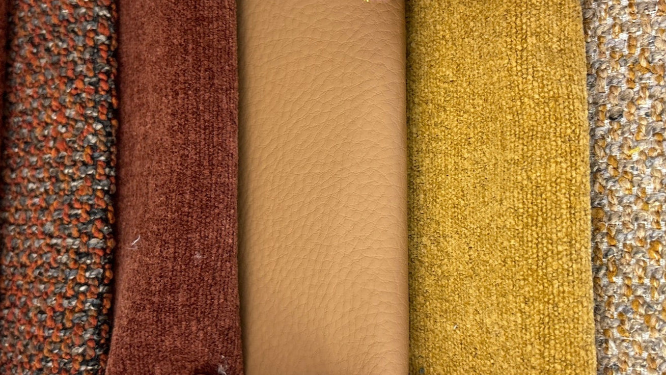 Stack of fabric swatches with hands holding them, showing a variety of textures and colors.