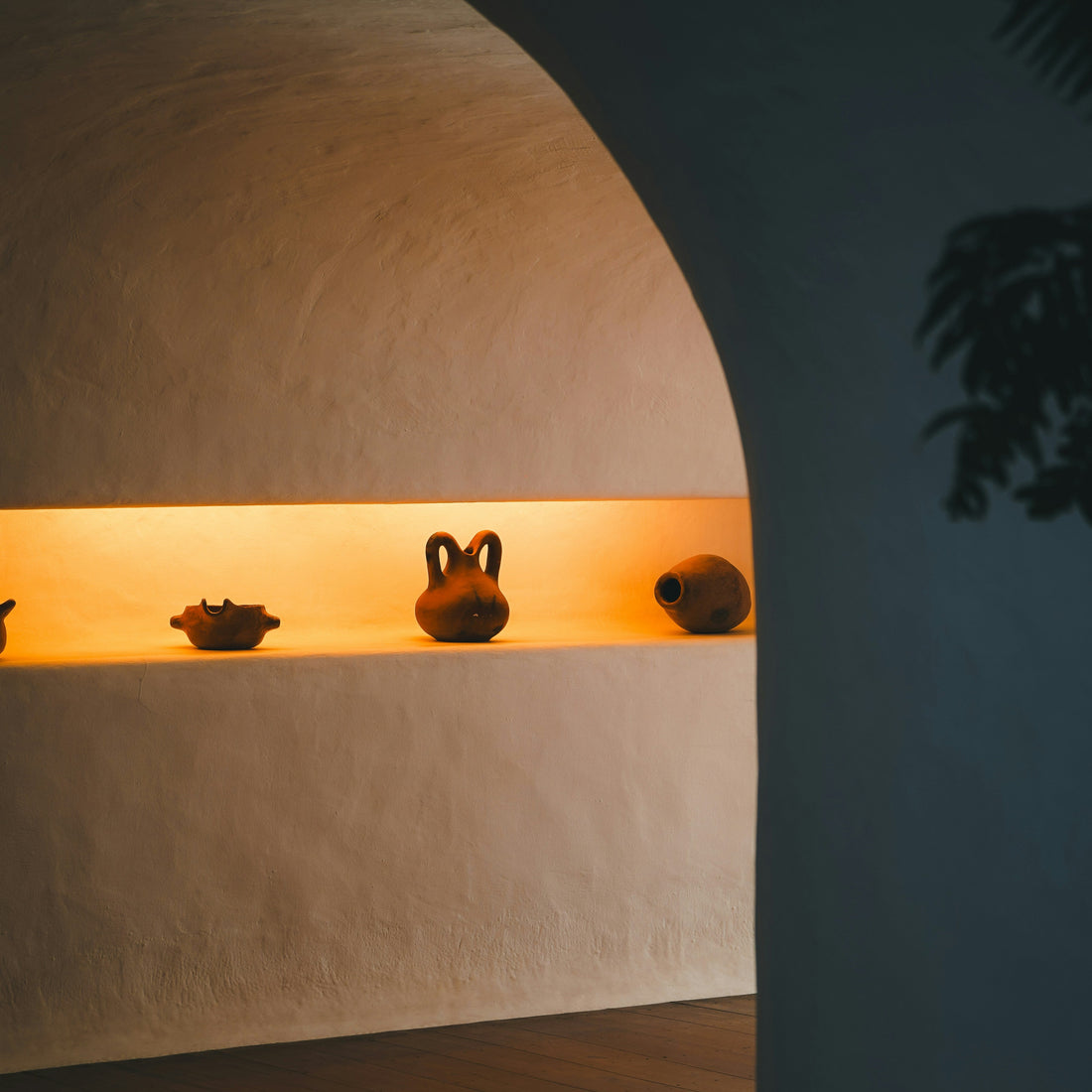 Ceramic pots on a shelf with warm lighting against a dark wall